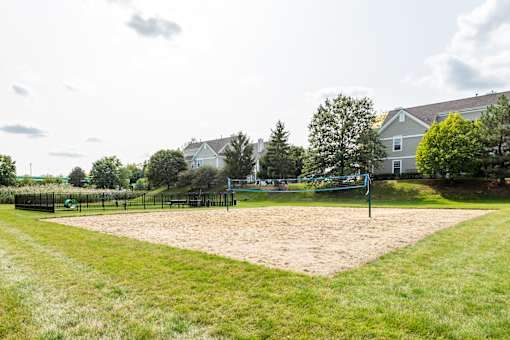 A sandy area in a park with a blue pole and a fence.