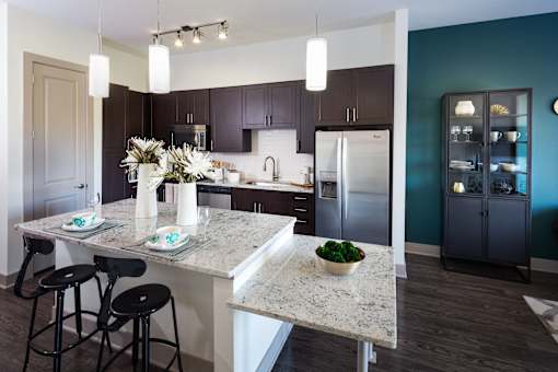A kitchen with a granite countertop and bar stools.