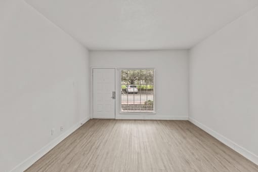 an empty living room with a door to a driveway