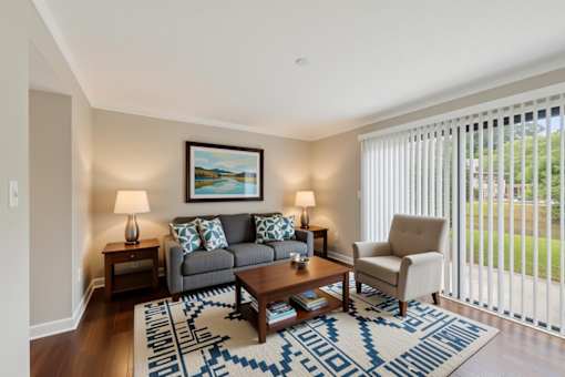 A living room with a grey couch, a coffee table, and a painting on the wall.