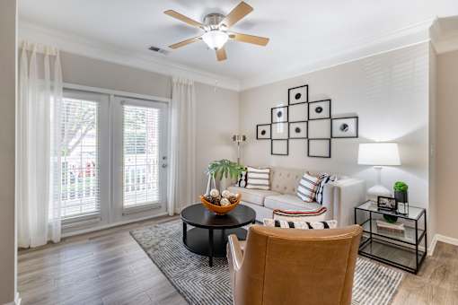 A living room with a ceiling fan, a sofa, a coffee table, and a chair.