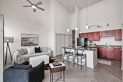 A modern living room with a white couch and a kitchen area in the background.
