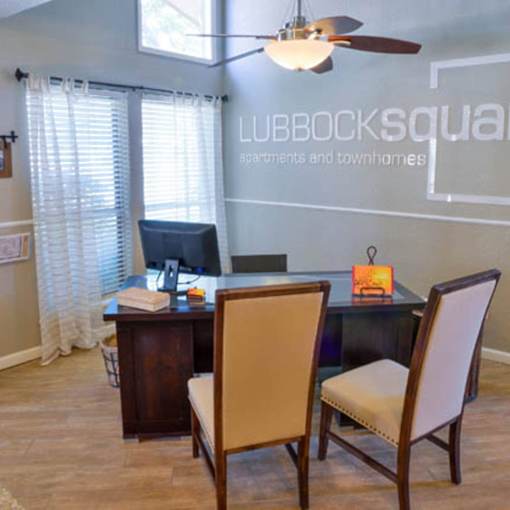 A conference room with a table, chairs and a ceiling fan.
