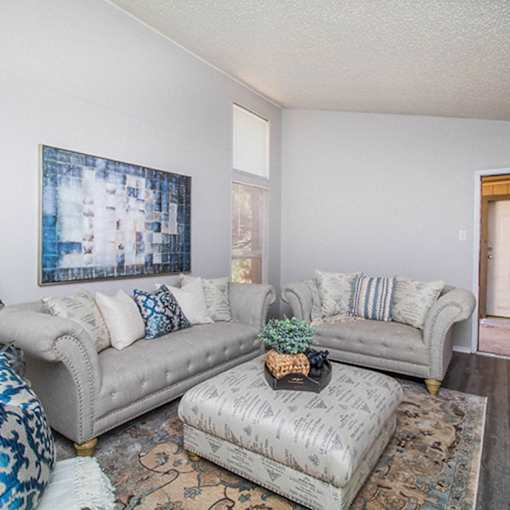 A living room with two couches and a patterned ottoman.