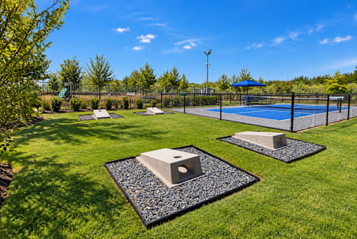 A backyard with a tennis court and two concrete objects on gravel.