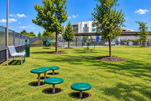 A sunny day at the park with green tables and a bench.