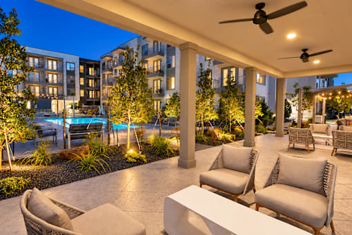 A patio with chairs and a table is illuminated by lights.