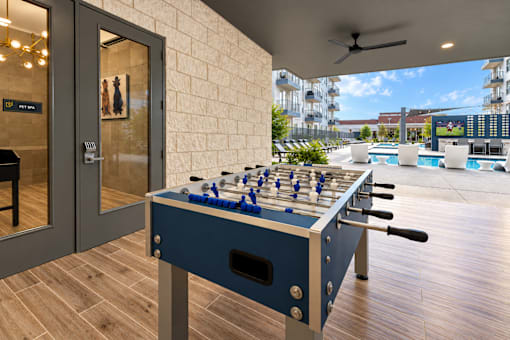 A foosball table is in the middle of a room with a pool table and a balcony.