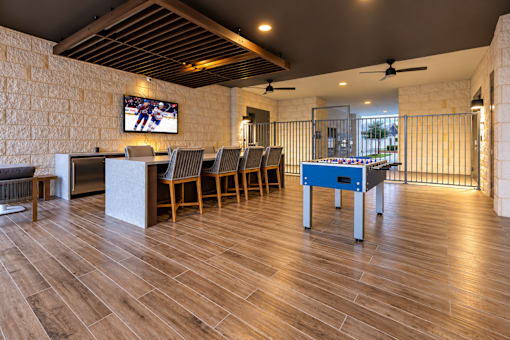 A room with wooden floors and a television mounted on a stone wall.