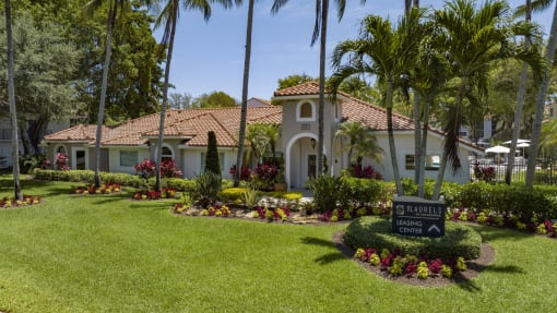 a house with palm trees and a sign in the yard