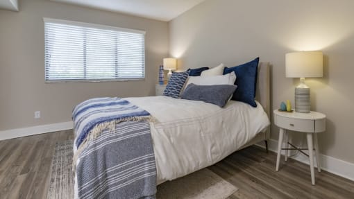 a bedroom with a bed with blue and white sheets and pillows