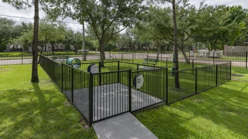 a wrought iron fence around a playground in a park