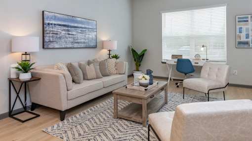 A living room with a beige sofa, a coffee table, and a painting on the wall.