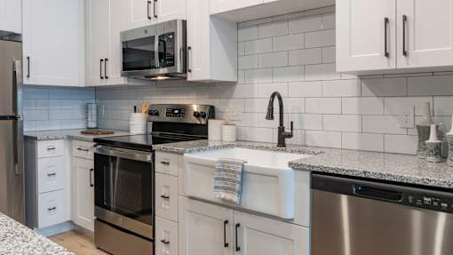 A modern kitchen with white cabinets and stainless steel appliances.