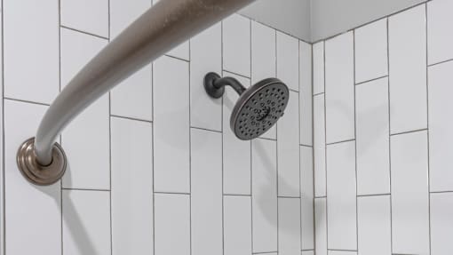 A shower head mounted on a white tiled wall.