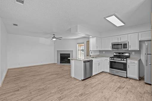 A spacious kitchen with a wood floor and white appliances.