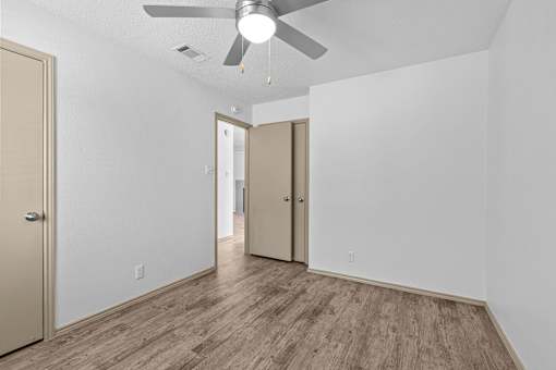 A room with a ceiling fan and wood flooring.