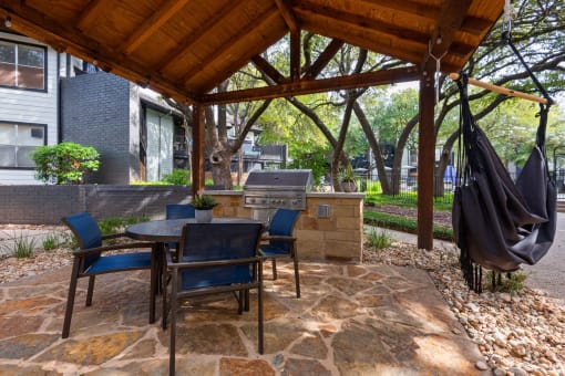 an outdoor kitchen with a grill and a table and chairs