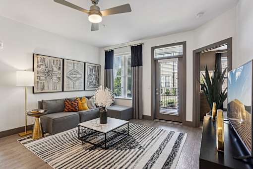 A living room with a grey couch, a coffee table, and a ceiling fan.