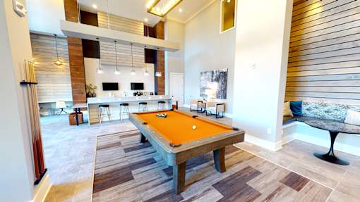 A pool table in a room with a bar and a kitchen in the background.