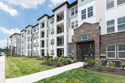 A row of modern apartment buildings with landscaped gardens in front.