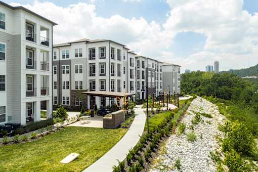 A row of modern apartment buildings with a gravel pathway in front.