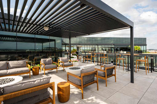 A patio with wooden furniture and a glass wall.