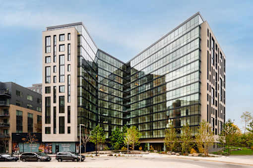 Two modern buildings with glass windows are situated next to each other.