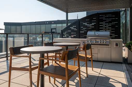 A table with chairs and a grill on a patio.