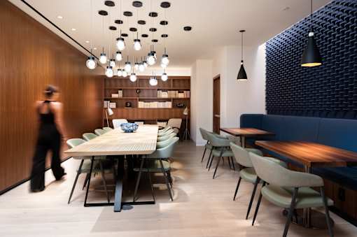 A woman walks past a dining table in a modern restaurant.