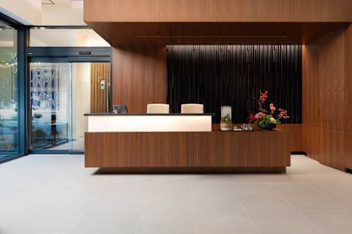 A reception desk with a laptop and a vase of flowers on top.