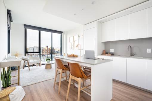 A modern kitchen with a wooden chair and a white counter.
