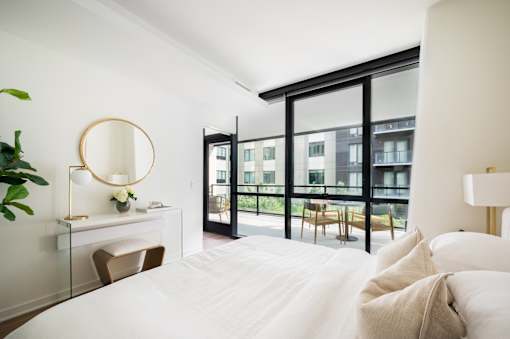 A bedroom with a large bed and a balcony.