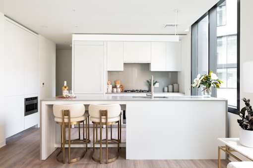 A modern kitchen with white cabinets and a bar area.