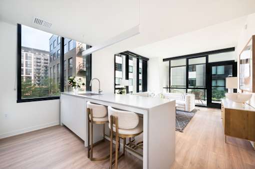 A kitchen with white countertops and wooden floors.