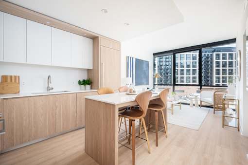 A modern kitchen with wooden chairs and a white island.