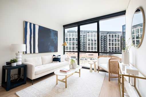 A living room with a large painting on the wall and a view of a cityscape through the windows.