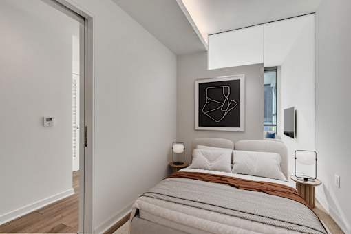 A bedroom with a bed, nightstand, and a painting on the wall.