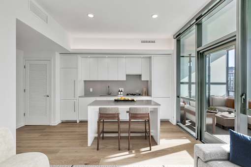 A modern kitchen with white cabinets and a dining table with chairs.