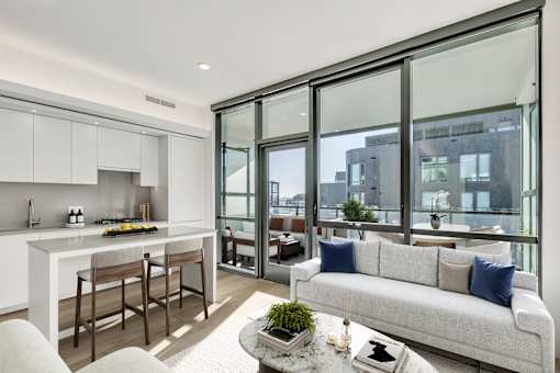 A modern kitchen with a bar and a couch with pillows.