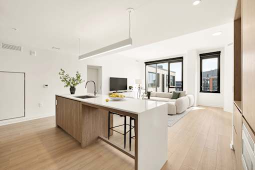 A modern kitchen with a wooden island and a dining area with a white couch.