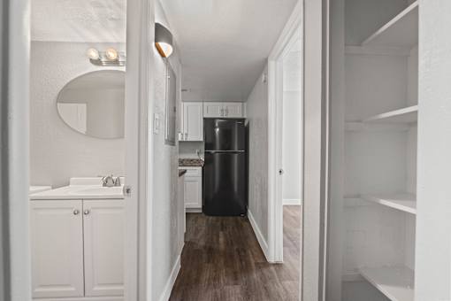 A white bathroom with a round mirror and a black trash can.
