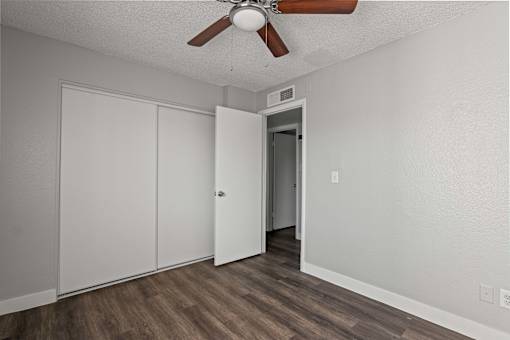 A room with a ceiling fan and a door leading to another room.