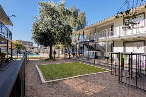A small grassy area in front of a building with a fence around it.