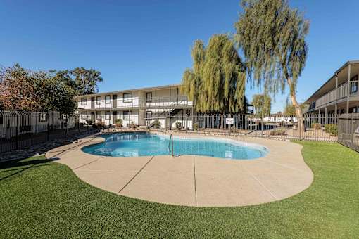 A swimming pool in a grassy area with a building in the background.