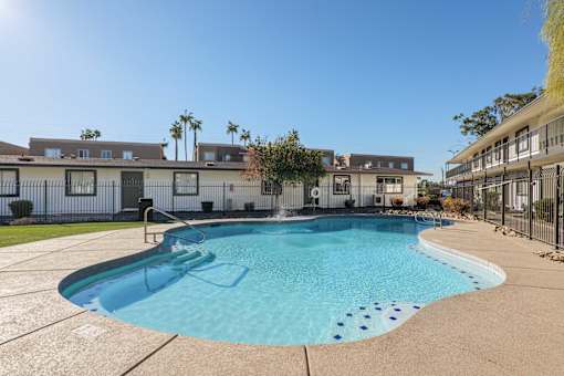 A swimming pool surrounded by a concrete floor and a fence.