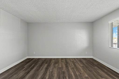 A room with wooden flooring and a window with blinds.