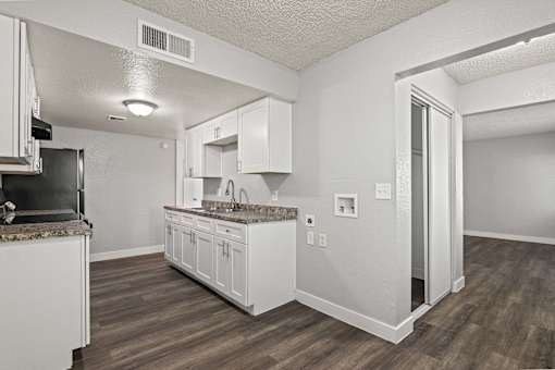 A kitchen with white cabinets and a granite countertop.