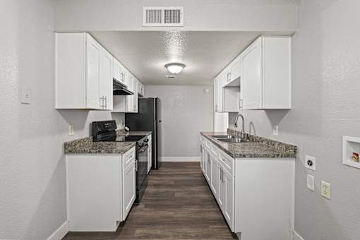 A kitchen with white cabinets and a granite countertop.