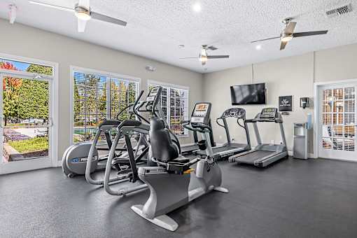 A gym with treadmills, elliptical machines, and a television.